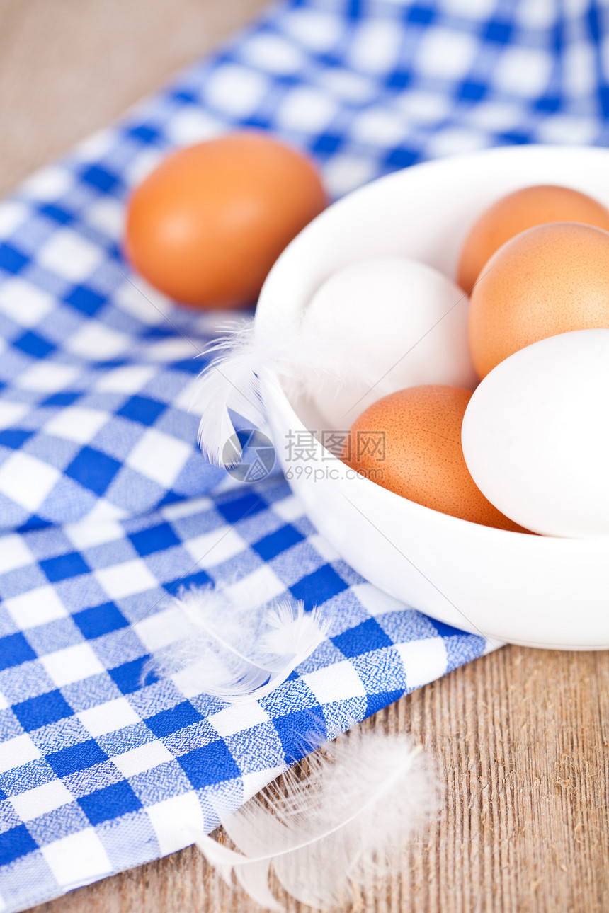 鸡蛋在碗里 毛巾和羽毛 在生锈的木制桌上图片
