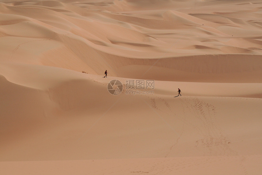 两人在撒哈拉沙漠中行走风景太阳晴天男人地球橙子气候沙丘干旱侵蚀图片