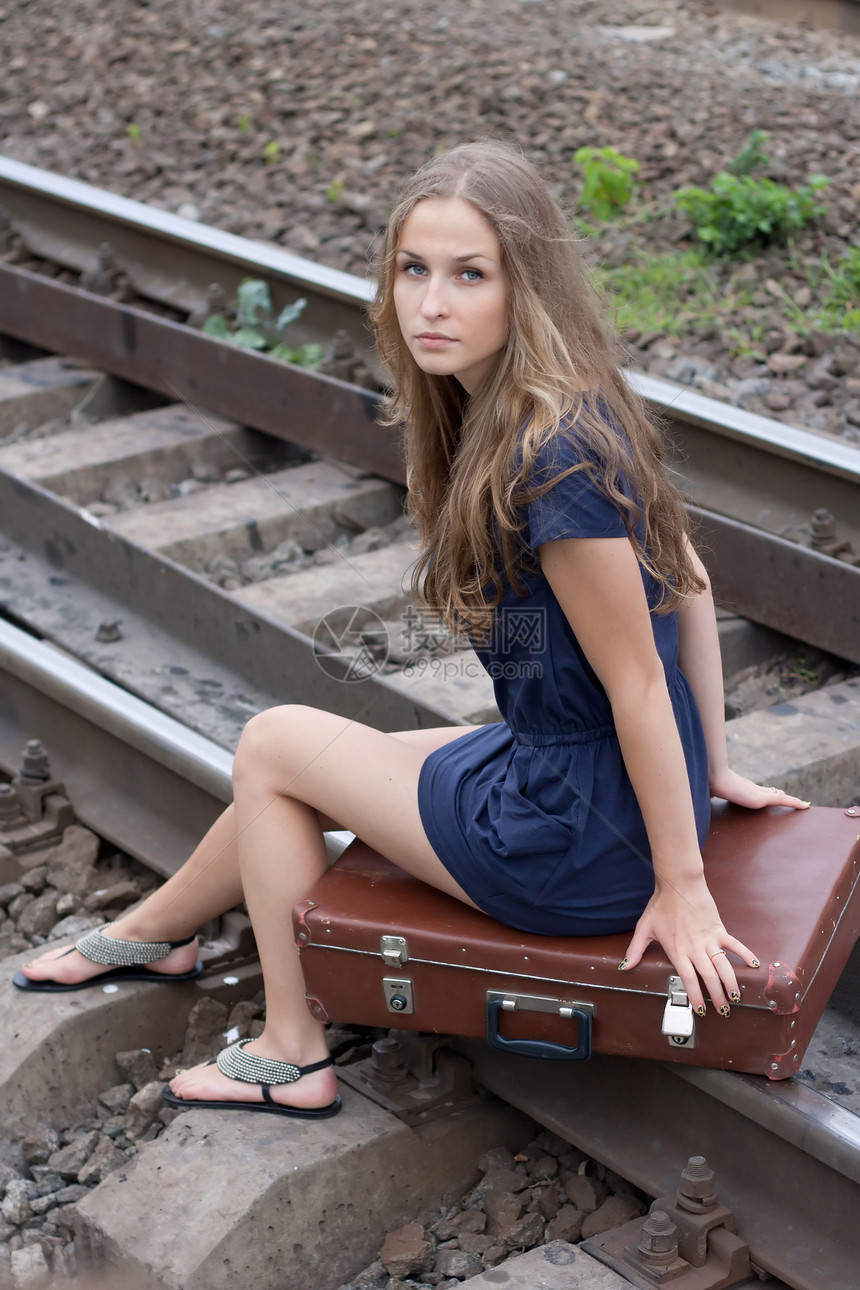 坐在铁轨上的妇女金发女郎旅行冒充运输女孩火车蓝色铁路裙子女士图片