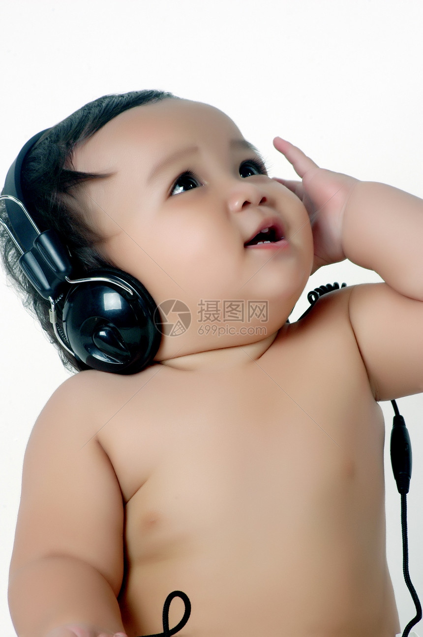 一个胖胖的小女孩 听音乐 用耳机戏服育儿领带赤脚皮肤女孩孩子工作室拳头快乐图片