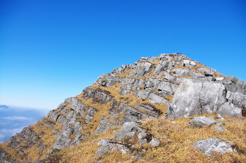 高山顶顶有岩石和草地青金石杂草稻草石头山顶登山高地山腰天空多云图片