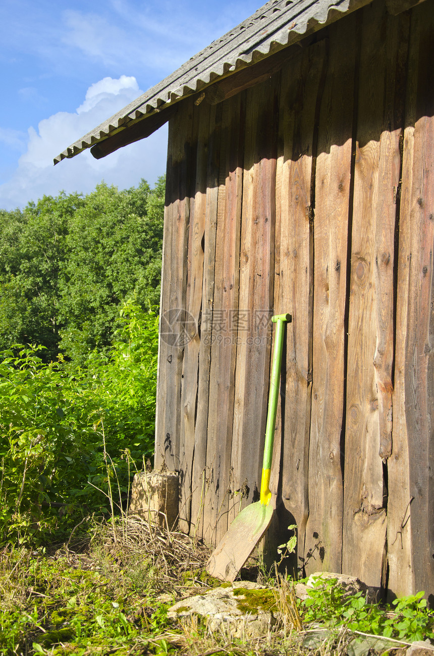 在夏季农场的铲子 靠近木制谷仓墙图片