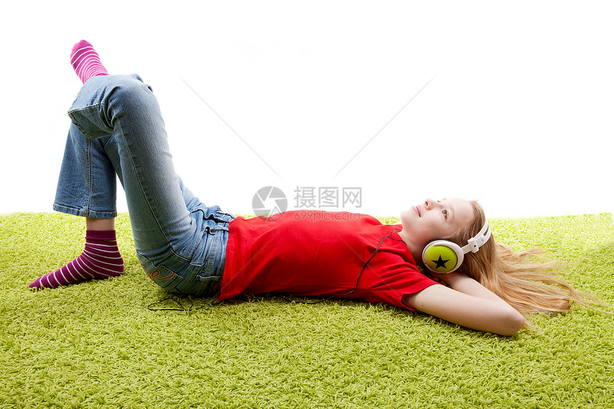 女孩正在听音乐 用耳机在说谎孩子绿色音乐地毯热情图片