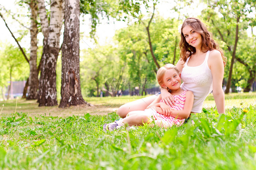 母亲和女儿一起坐在草地上花园妈妈成人公园女孩家庭地面女士女性圆圈图片