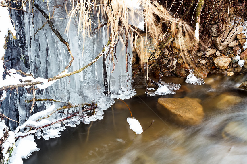 冬天在一棵木林中喷射冰冻的河水图片