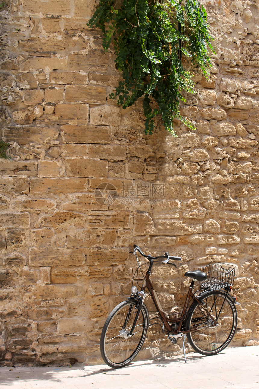 自行车靠旧墙倾斜图片