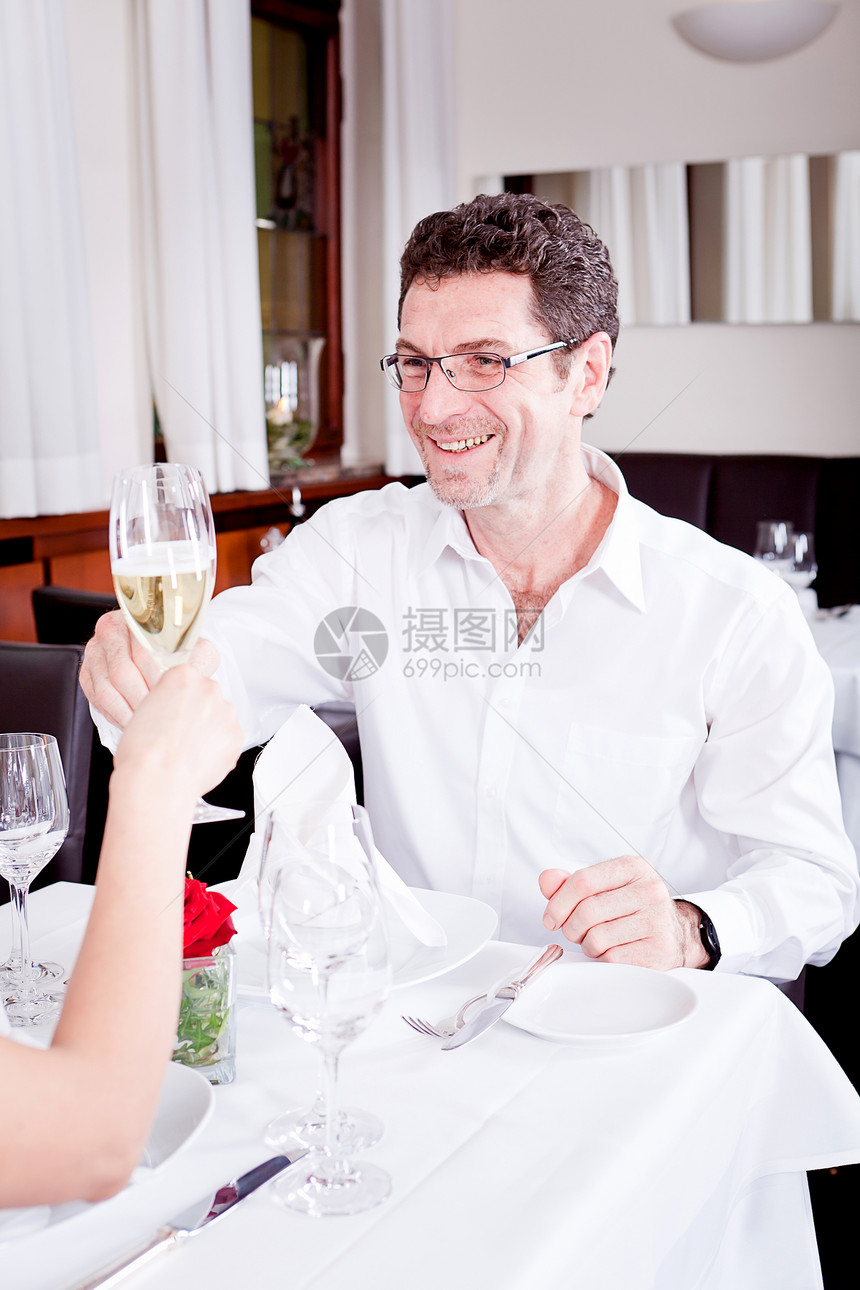 在餐厅欢庆快乐的一对笑着微笑的情侣恋人眼镜推介会浪漫纪念日用餐成人男人玻璃周年图片