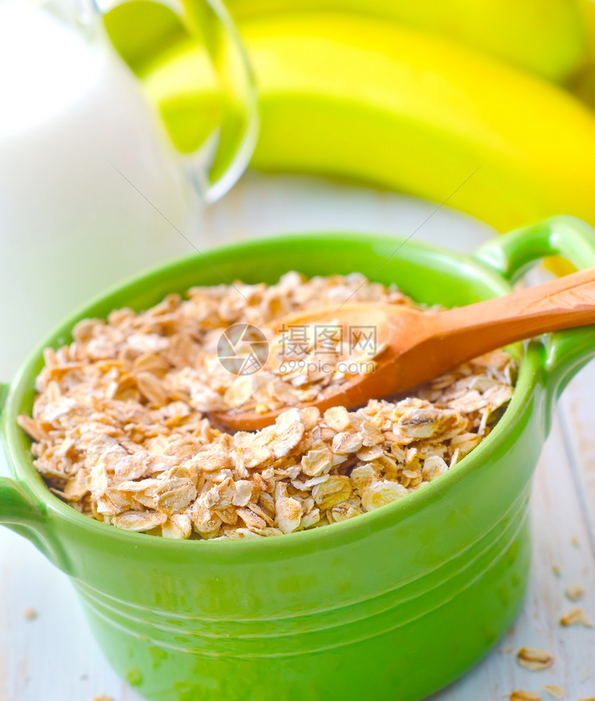 绿碗中含香蕉和牛奶的煤炭片片饮食木头早餐谷物玉米木板水果食物薄片宏观图片