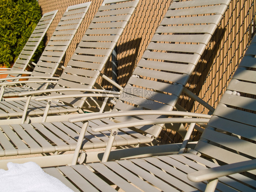 泳池旁的休息椅波纹游客叶子栏杆休息室游泳家具蓝色躺椅灌木图片