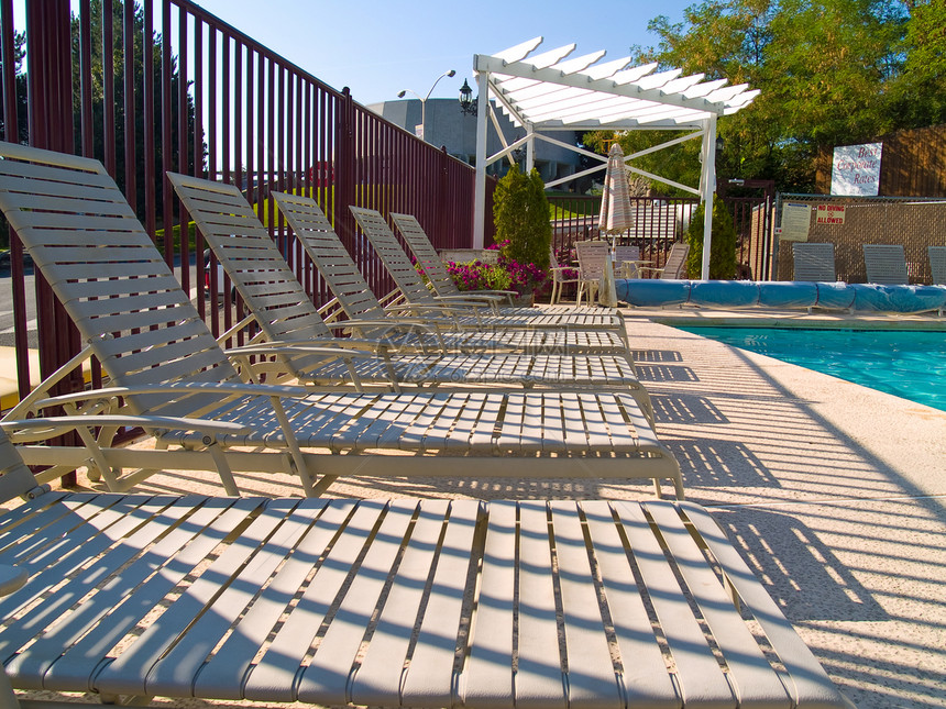 泳池旁的休息椅栏杆波纹水池假期叶子游泳日光浴躺椅栅栏蓝色图片