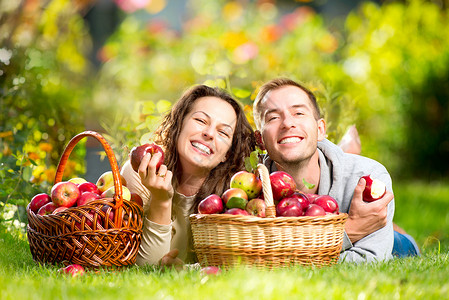 一对夫妇在秋园的草和吃苹果上放松女士男生果园食物男人活动家庭水果乐趣卫生背景图片