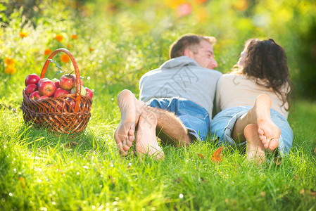 一对夫妇在秋园的草和吃苹果上放松水果家庭牙科收成男人饮食果园花园活动食物背景图片