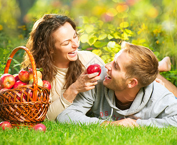 一对夫妇在秋园的草和吃苹果上放松家庭保健男人牙科乐趣花园女孩男生篮子食物背景图片