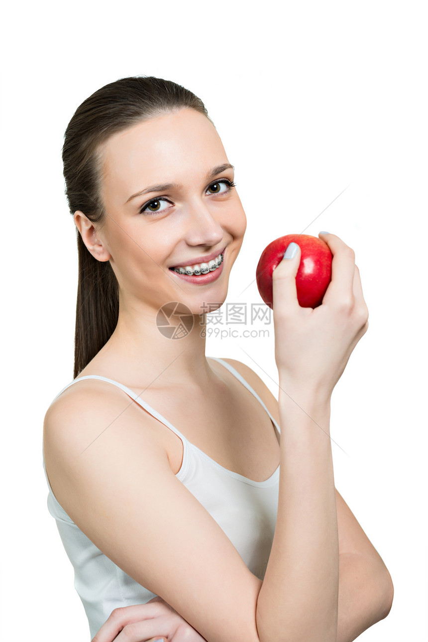 长着苹果和括在牙齿上的年轻妇女图片