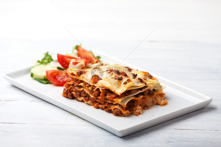 方块上的意大利千层面面条脆皮白色西红柿食物叶子烹饪盘子牛肉褐色正方形图片