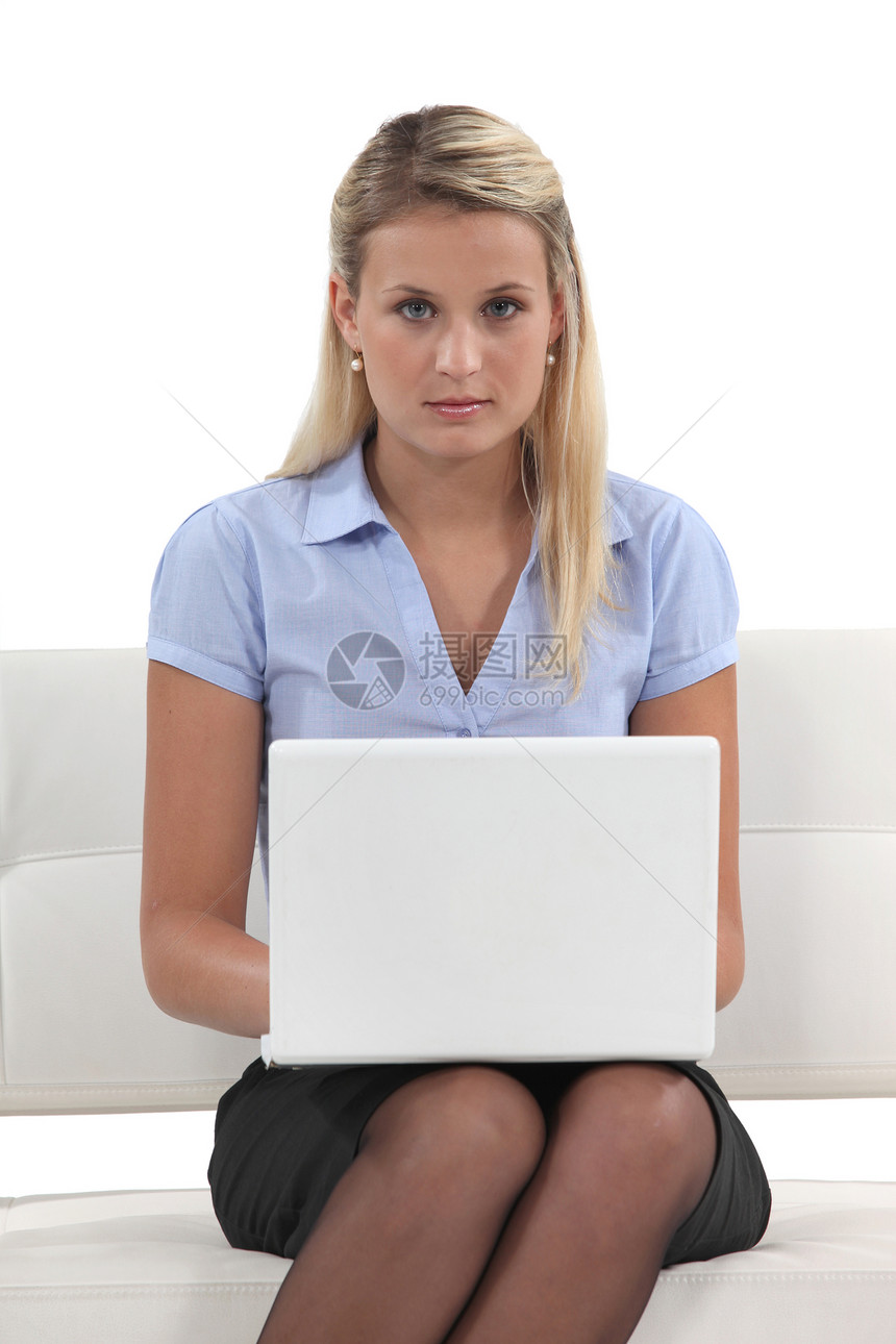 年轻妇女在沙发上用笔记本电脑长椅机动性管理人员女士商务工人衣领白色女性互联网图片