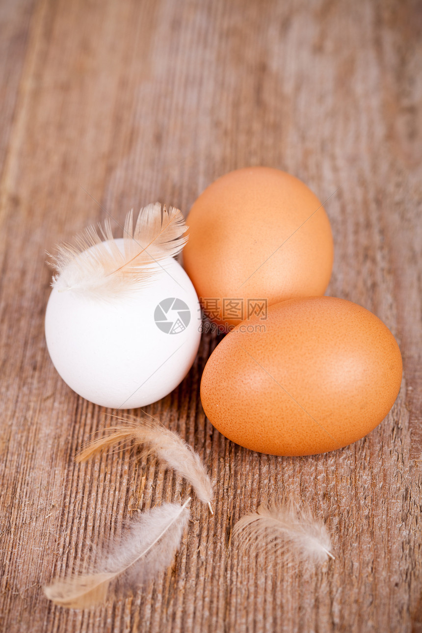 三只鸡蛋和羽毛食物棕色营养桌子乡村白色厨房木头斑点图片