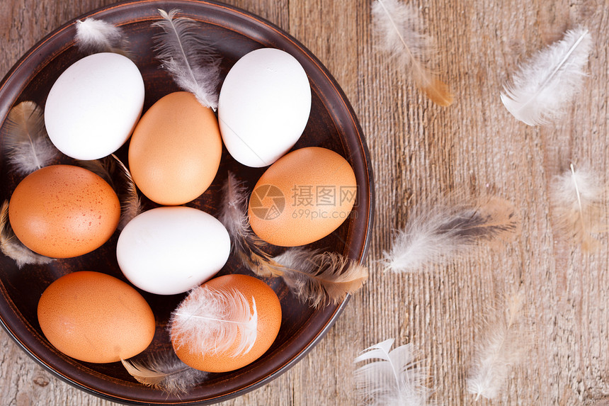 盘子里的鸡蛋和羽毛棕色白色陶瓷乡村桌子营养木头斑点制品食物图片