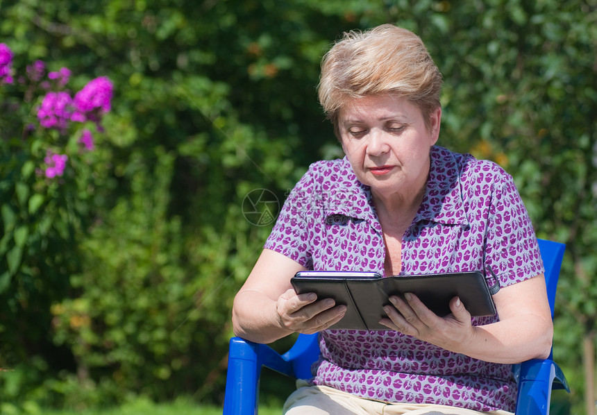 有电子书的女人信息机动性阅读电子产品成人花园老年街道花朵图书图片