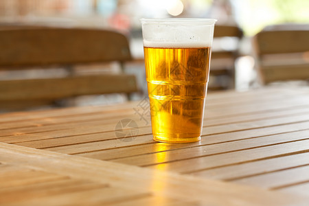 贮藏啤酒站在木制桌上的啤酒托盘酒吧庆典餐厅酒精泡沫花园桌子派对金子背景