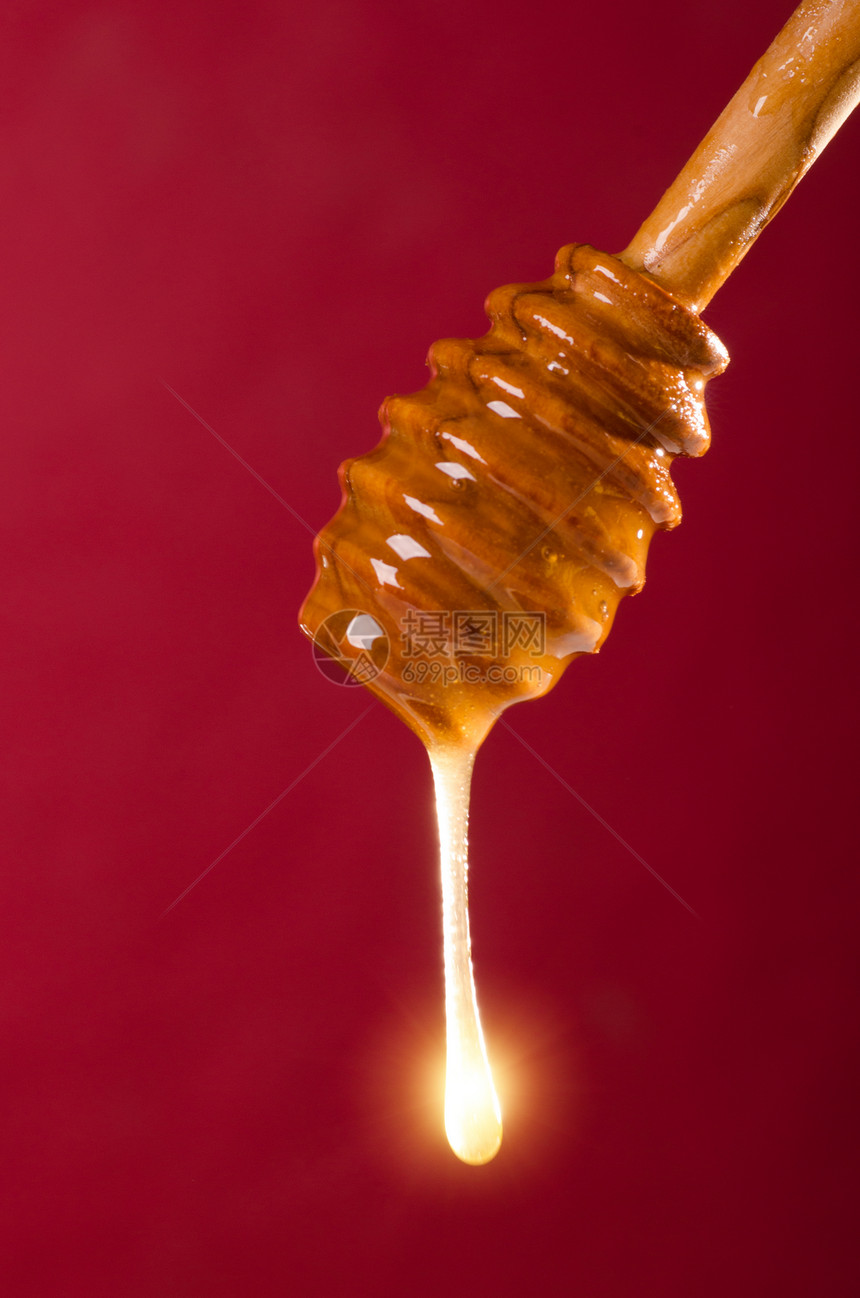 彩色背景上的蜂蜜勺子金子液体味道玻璃辉光太阳饮食美食食物毛毛雨图片