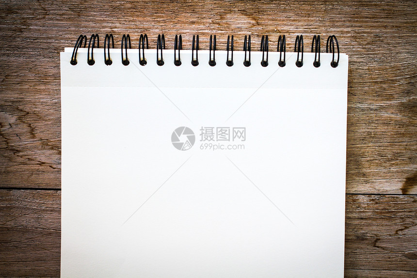木头背景上的笔记本粉色笔记白色图片