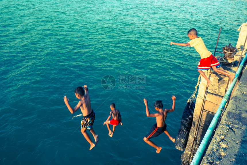 孩子在鱼码头上 跳到海边图片