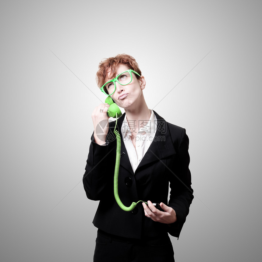 使用绿色手机的可疑商业妇女图片