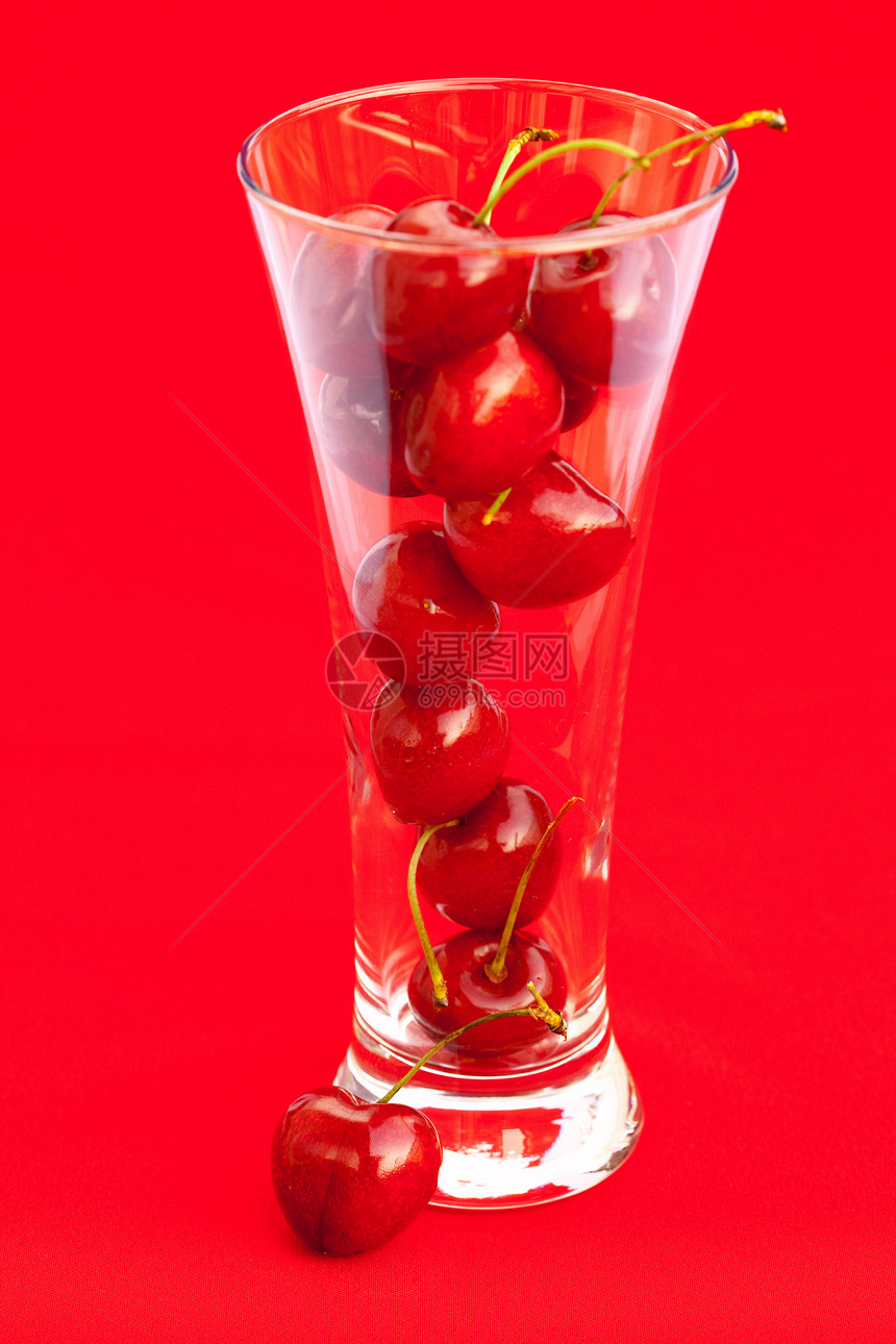 红色背景上有樱桃的玻璃杯图片