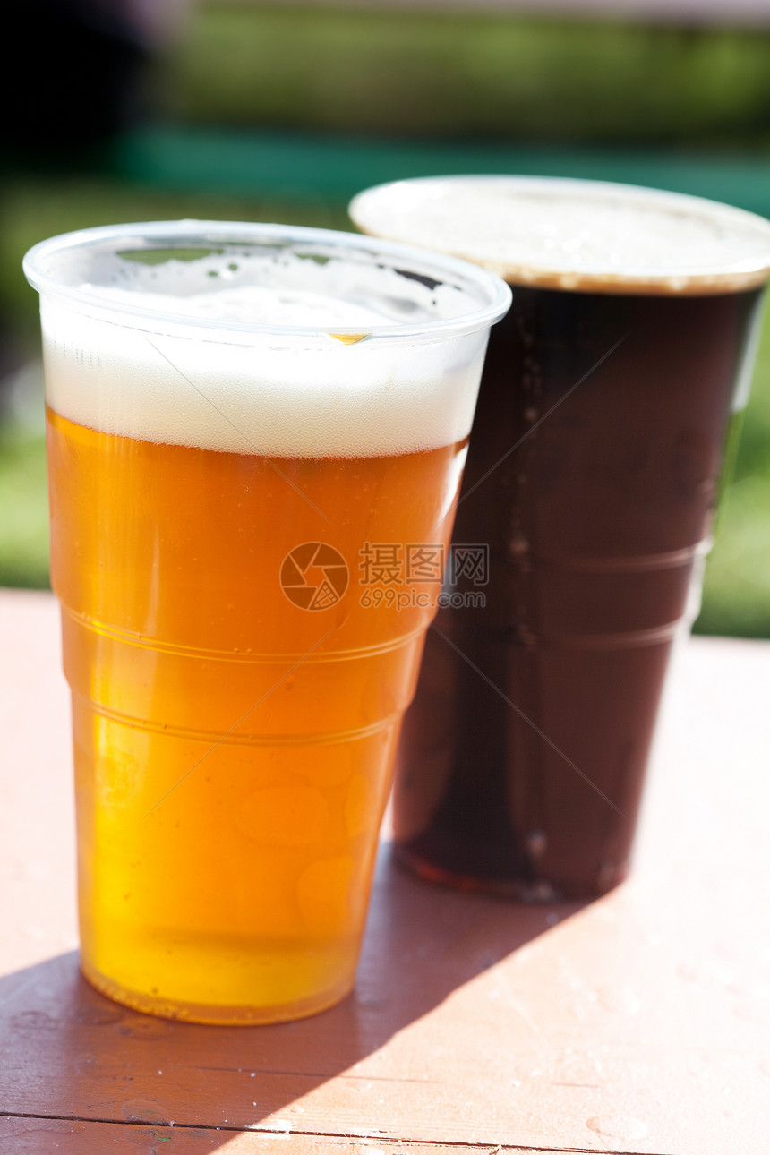 桌子上闪光和黑啤酒的玻璃杯液体派对木头酒精泡沫啤酒玻璃庆典琥珀色托盘图片