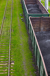 配煤粉的货运车工业进口运输出口煤炭灰尘铁路草地地面火车背景