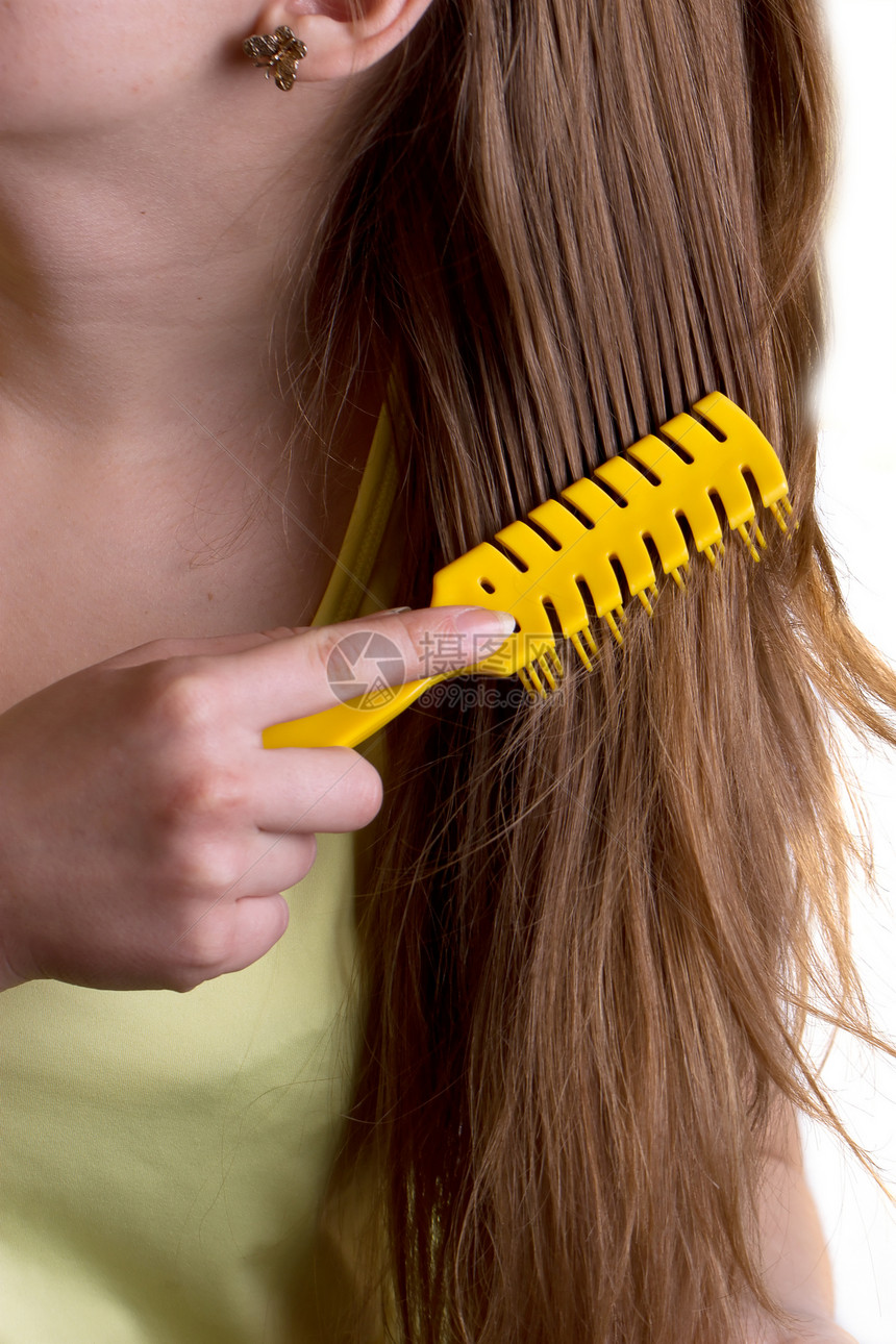 妇女梳梳头发的黄色梳子图片