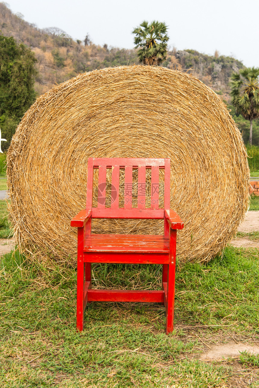 用红椅子在绿草上堆成大片干草图片
