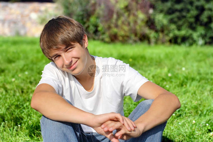 快乐的青少年树木休息男性天气棕色草地公园晴天牛仔裤青年图片