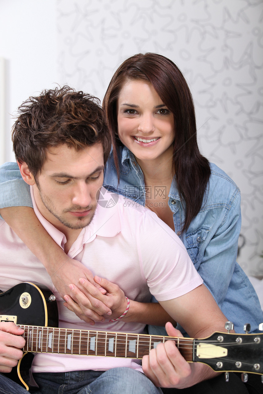 年轻夫妇在家里弹吉他唱歌韵律吉他吉他手乐器青少年学习情人男人微笑图片