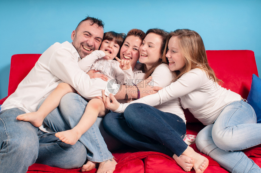 幸福的家庭在沙发上女士男生父亲孩子孩子们母亲拥抱父母女孩男性图片