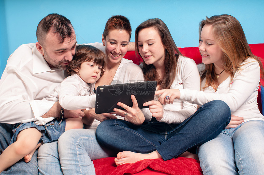 在沙发上用平板电脑乐趣父亲母亲幸福女士父母女孩白色药片感情图片