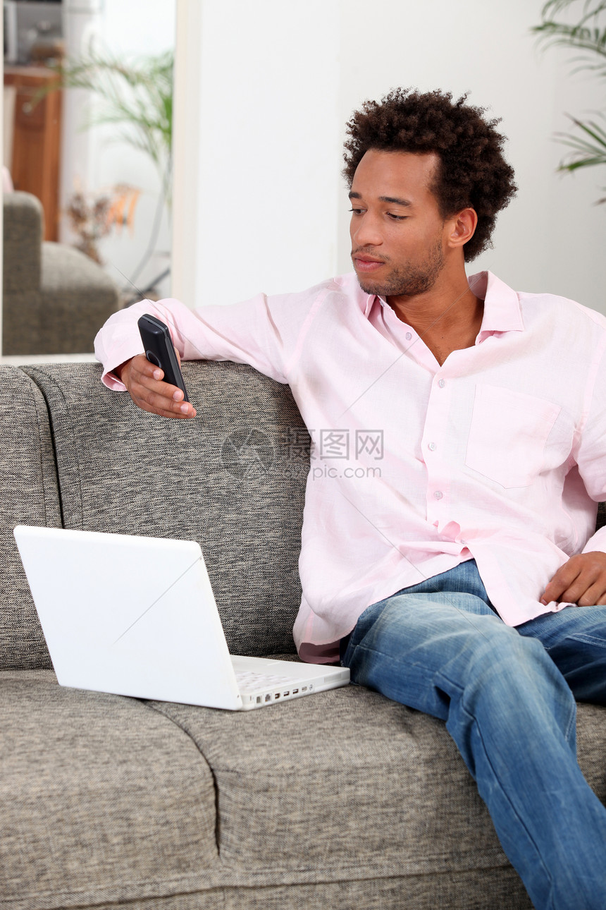 男人在沙发上放松办公电话长椅笔记本桌子牛仔裤照片房间房子工作图片