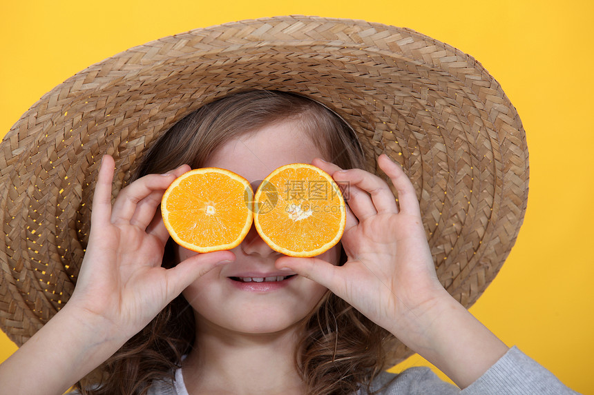 年轻女孩当着眼睛拿着橘子切片图片