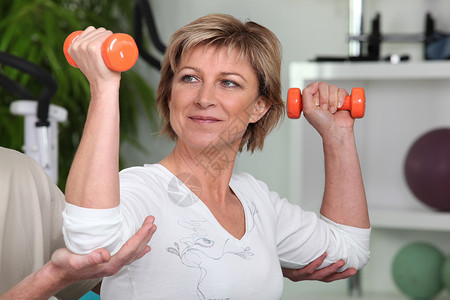 具有橙色重量的妇女辅导植物架权重运动班级前臂女性体育锻炼培训师出汗背景图片