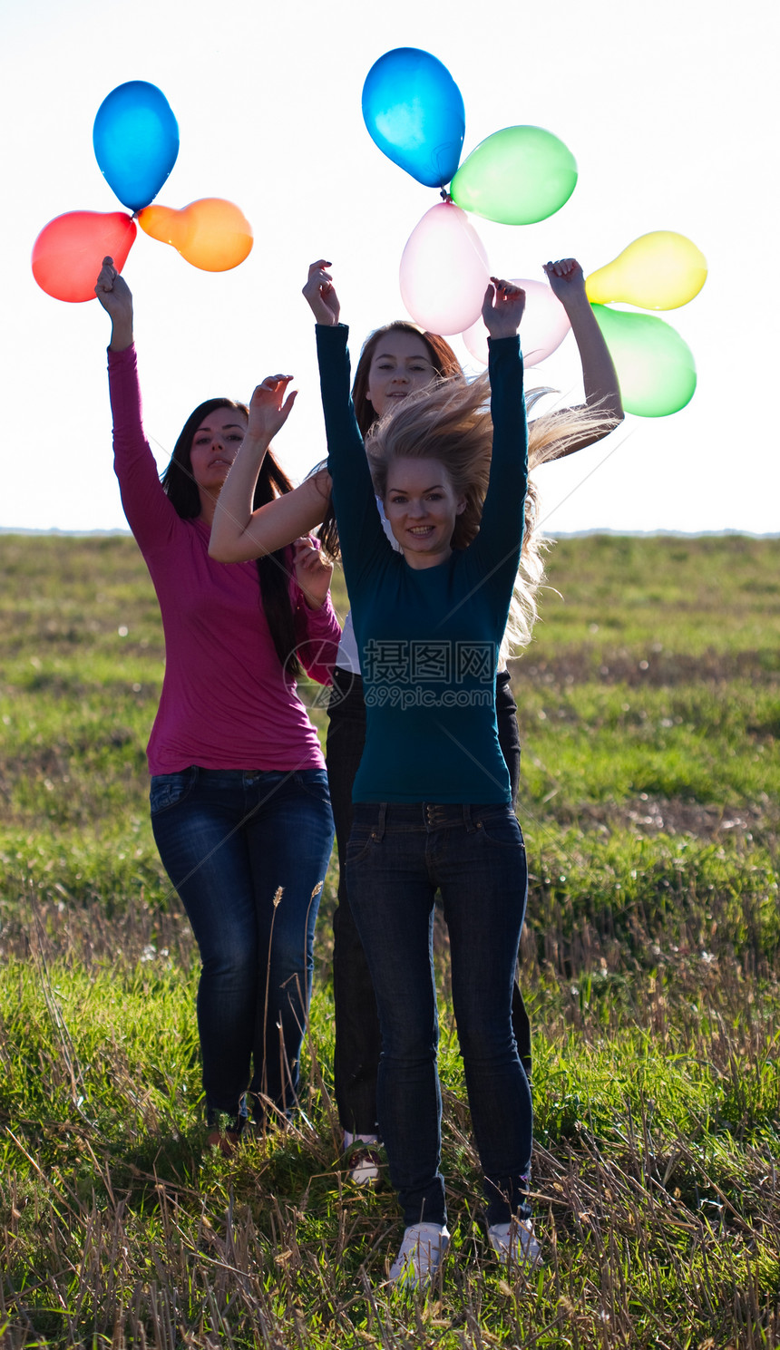 三名美丽的年轻女子 带着气球进入田野对抗喜悦快乐场景闲暇蓝色自由草地女孩们幸福微笑图片