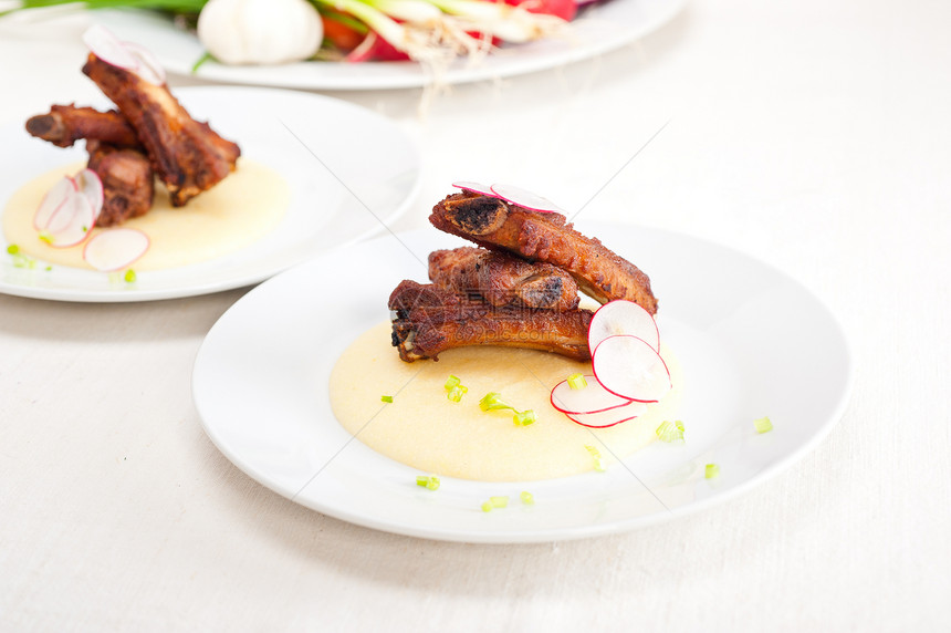 波伦塔玉米奶油床上的猪排肋骨油炸红色食物蔬菜空闲盘子猪肉午餐玉米图片
