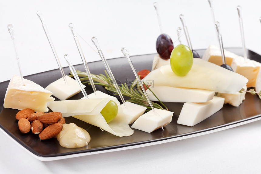 具有不同类型奶酪的板板羊乳食物自助餐盘子派对迷迭香脆皮草本植物榛子坚果图片