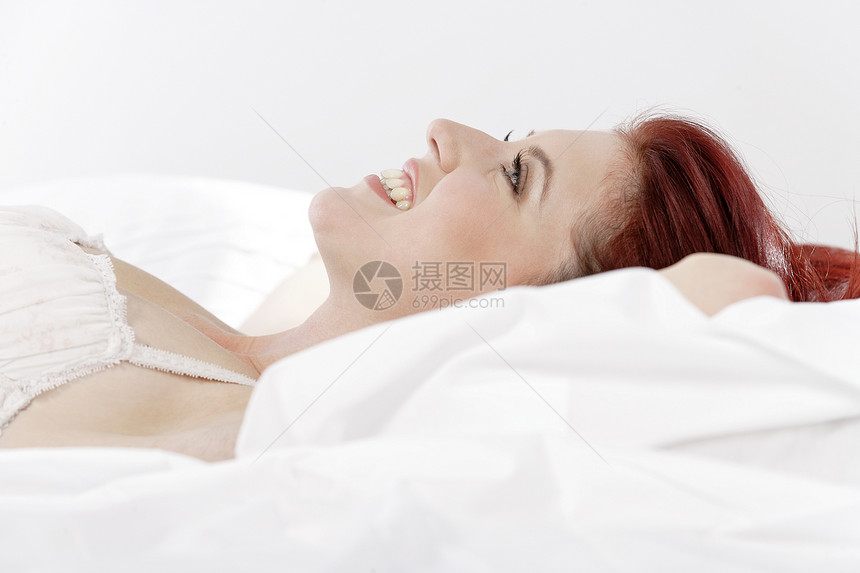 妇女穿着内裤躺在床上女性快乐女士内衣枕头微笑羽绒被图片
