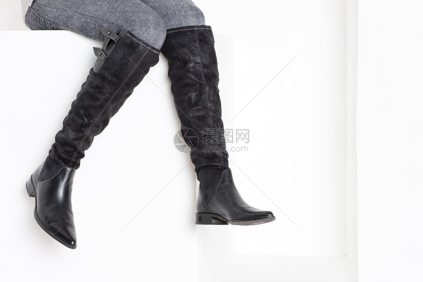 穿着时装靴子的女坐妇女黑色内饰人士鞋类单身成人女性成年人绑腿女士图片