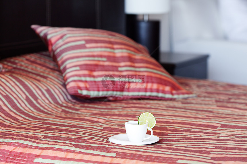 床铺上有两个枕头 毯子上还有一杯茶柠檬停留来源食物亚麻软垫床单国王气氛卧室图片