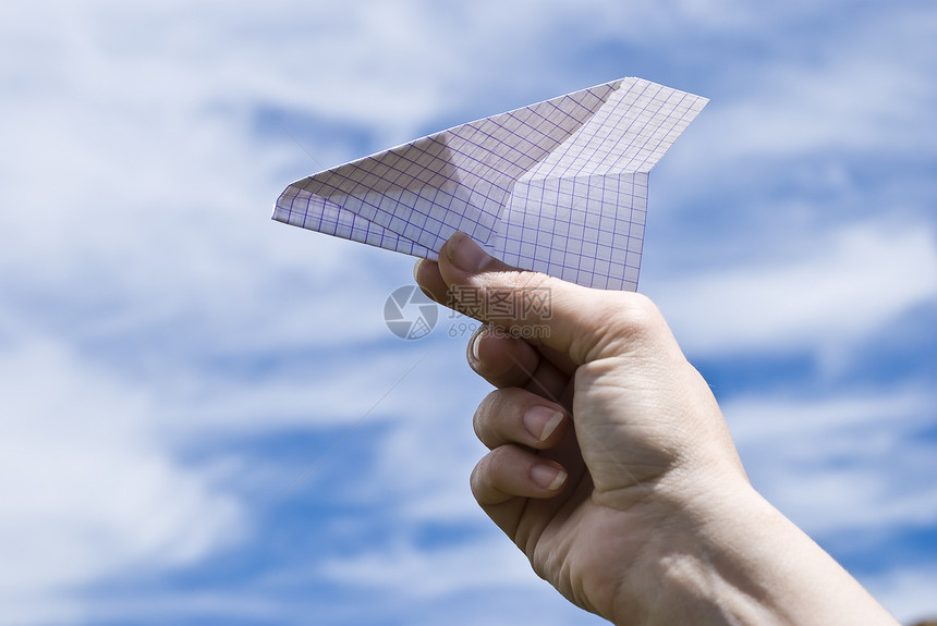 手持天空背景的纸式飞机图片