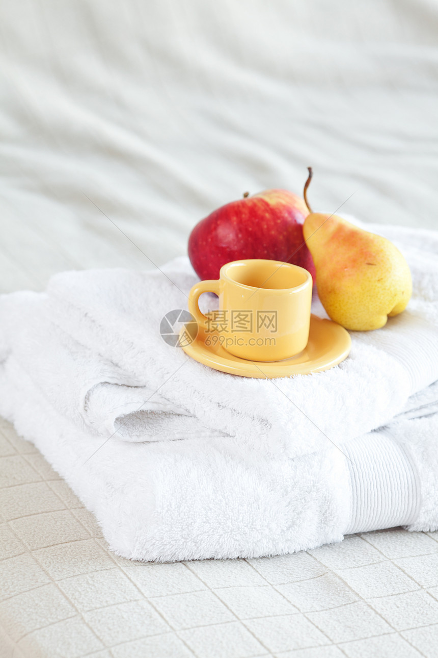 杯子 苹果和梨子 放在床上的毛巾上图片