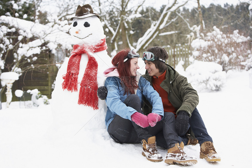 冬季风景中的青少年情侣 下到雪人围巾微笑女孩男生寒冷女性金发季节笑声热饮图片