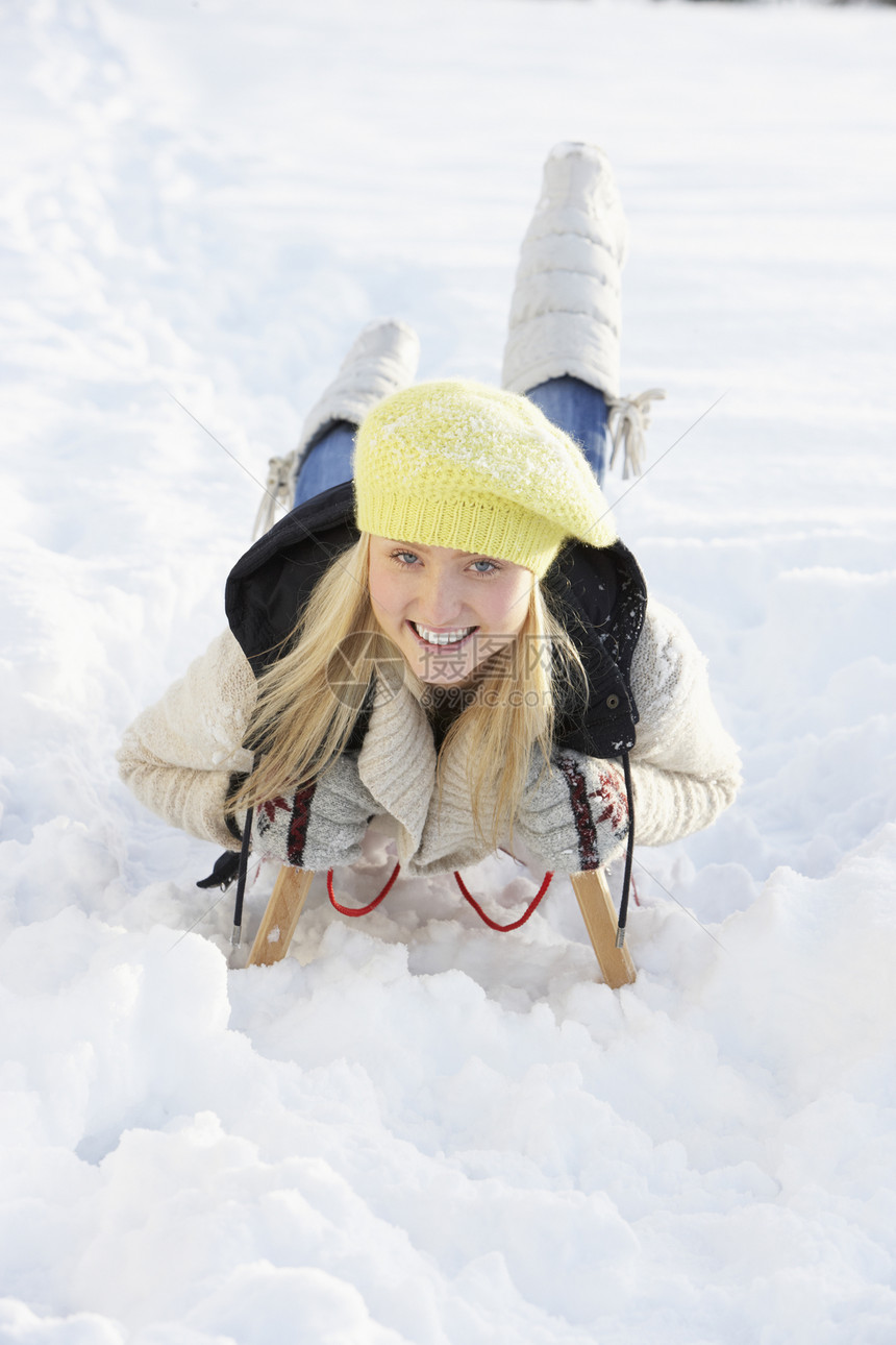 在雪地风景中的滑雪上骑车的少女围巾笑声场地季节寒冷青少年雪橇微笑帽子金发图片